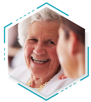 A smiling older woman stands beside a young woman, both radiating joy and warmth in their expressions.