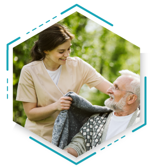 An elderly man receives help from a nurse in a park, highlighting compassion and care in a natural environment.