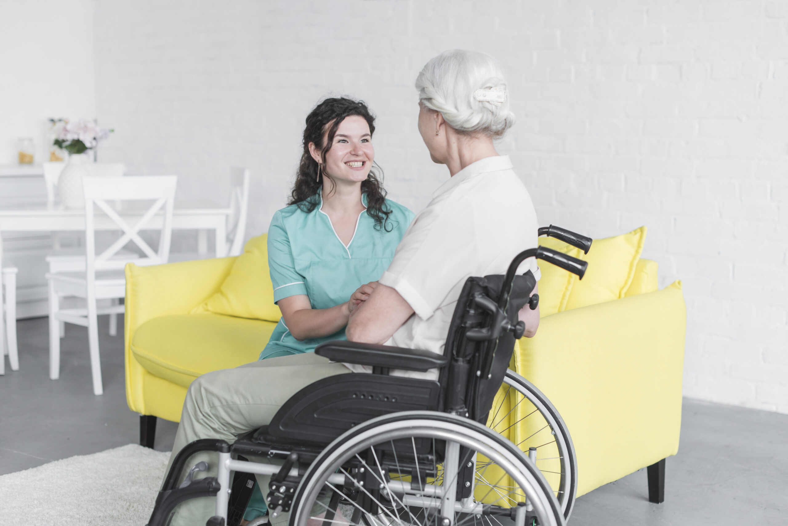 Smiling caregiver looking at a senior woman sitting in a wheelchair